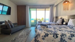 Et moderne hotelværelse med en stor seng, en sofa, et fjernsyn og en balkon med udsigt.