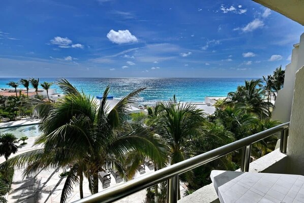A balcony with a view of a beach and a pool area.