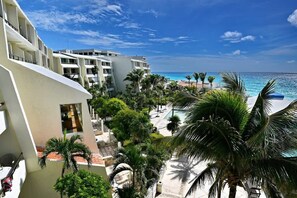 A resort with a pool, palm trees, and a view of the ocean.