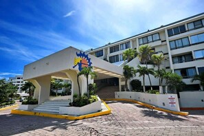 Entrada de hotel con un logotipo distintivo, un área de espera cubierta y una escalera que conduce al edificio.