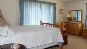 A bedroom with a bed, a wooden nightstand, a dresser, a mirror, and a ceiling fan. - Quiet-Country and Spacious Grandma's Duplex (Stamping Ground)