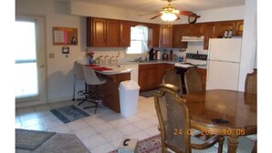 A kitchen with wooden cabinets, a dining table, and a ceiling fan. - Quiet-Country and Spacious Grandma's Duplex (Stamping Ground)