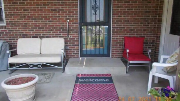 A brick exterior with a welcome mat, two white sofas, and a red chair. - Quiet-Country and Spacious Grandma's Duplex (Stamping Ground)