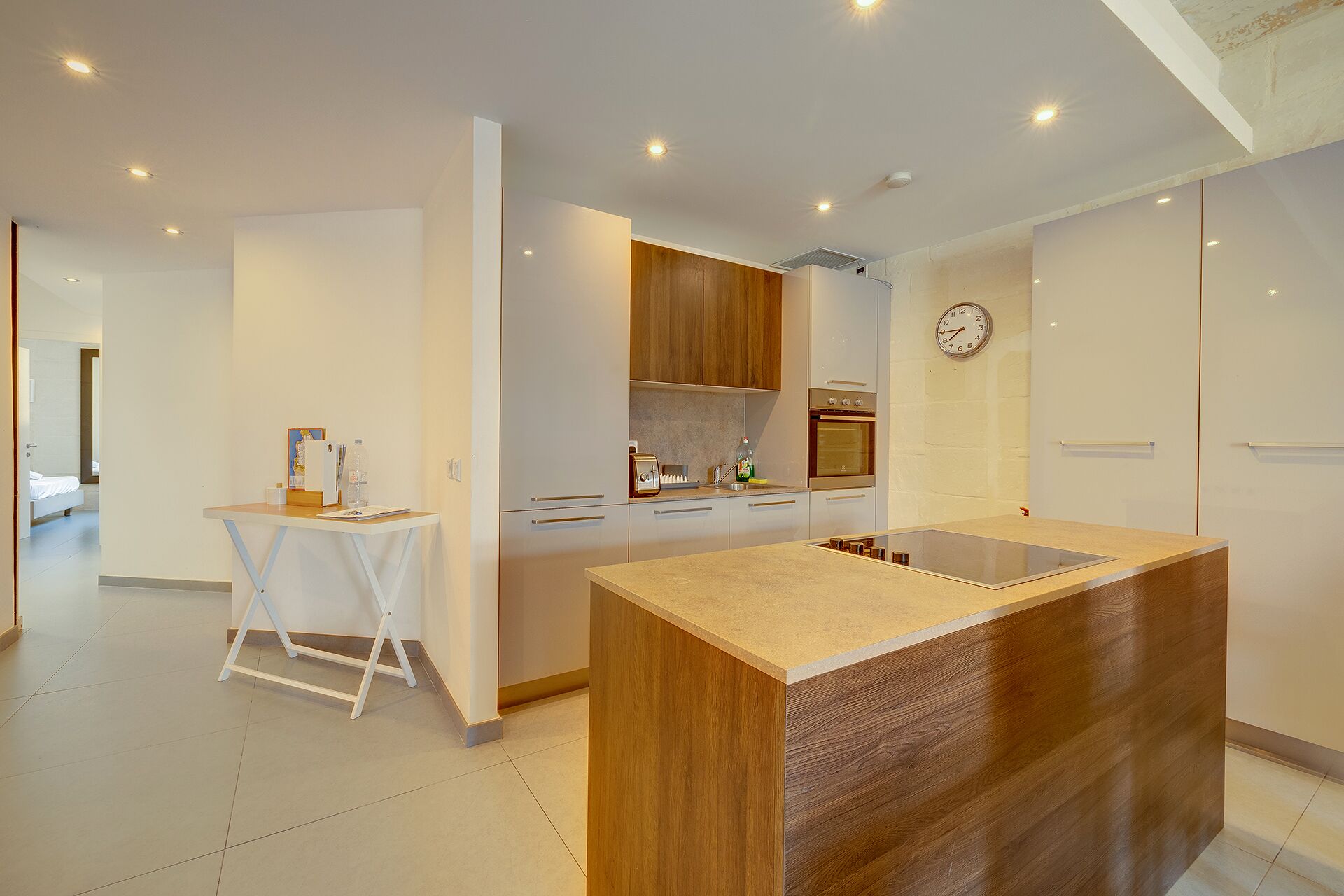 A modern kitchen with a central island, wooden cabinets, and a built-in oven.