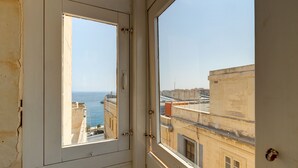 Une fenêtre donnant sur la mer et les bâtiments.