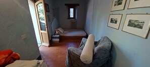 Ein schmaler Raum mit einem Bett, einem Heizkörper und gerahmten Bildern an der Wand.