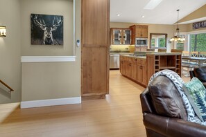 A spacious kitchen with wooden cabinets, a dining area with a table and chairs, and a large window providing a view of the outdoors. - Deschutes Riverfront Home with A/C, Game Room, Hot Tub, Kayaks and Trails (Bend)