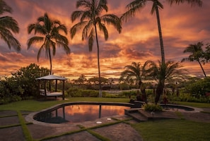 A serene outdoor setting with a swimming pool, palm trees, and a gazebo.