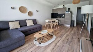 Un salón moderno con un sofá gris, una mesa de centro redonda y suelo de madera.