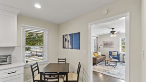 A dining area with a table and chairs, a kitchen with a toaster, and a living room with a sofa and a coffee table. - 3BR Near Swamp Rabbit Trail • Fenced Yard • Pet-Friendly • 7 Min to Downtown (Greenville)