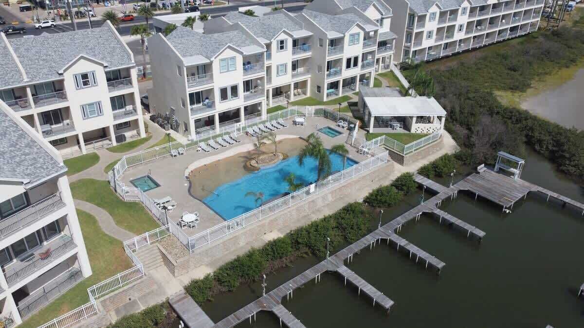 Un hotel de varios pisos con piscina, mobiliario exterior y zona de embarcadero.
