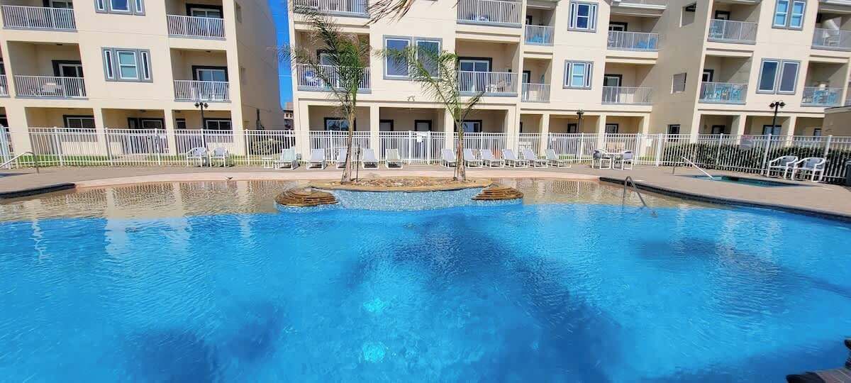 Ein Swimmingpool mit Liegestühlen und ein Gebäude mit Balkonen im Hintergrund.