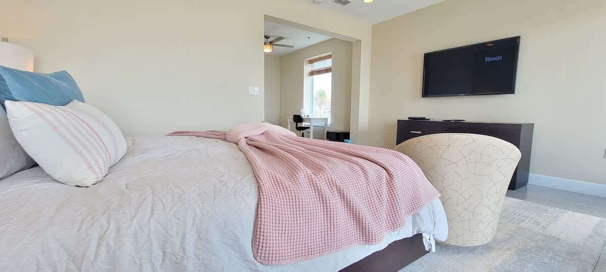 A bedroom with a bed, a TV, a desk, and a chair.