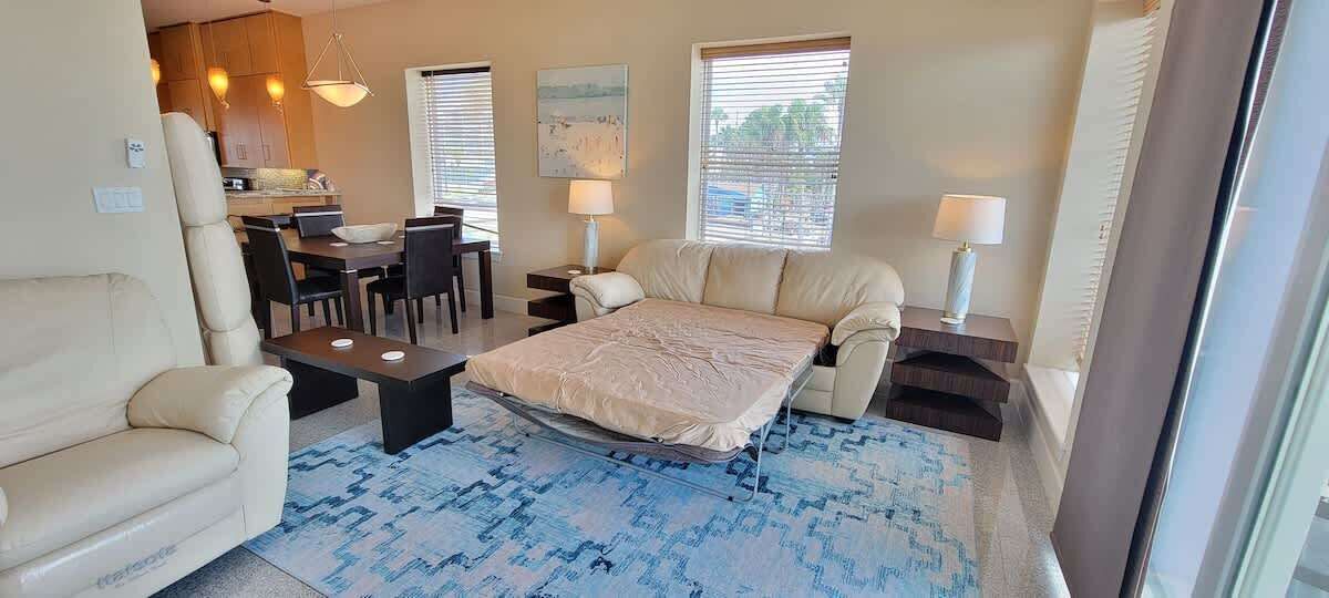 Un espacio habitable pequeño con cama, sofá, mesa de comedor y sillas.