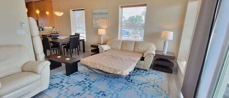 Un espacio habitable pequeño con cama, sofá, mesa de comedor y sillas.