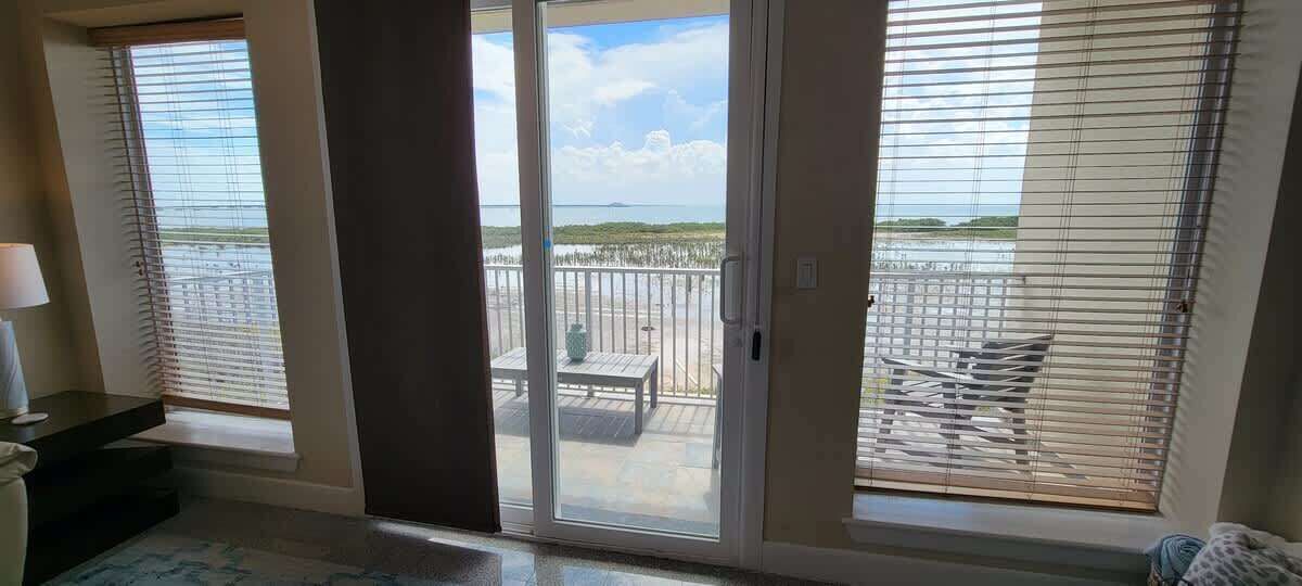 Une pièce dotée d’une porte-fenêtre coulissante donnant sur un balcon avec vue sur la plage et l’océan.