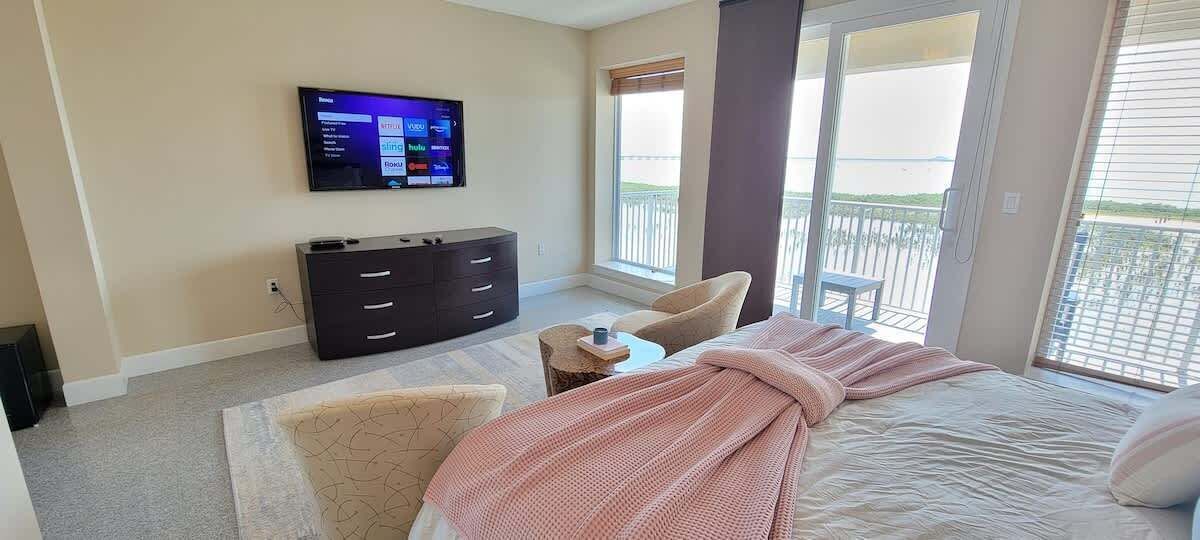 Ein Hotelzimmer mit Bett, Wandfernseher, Kommode, Sessel und Balkon mit Blick.