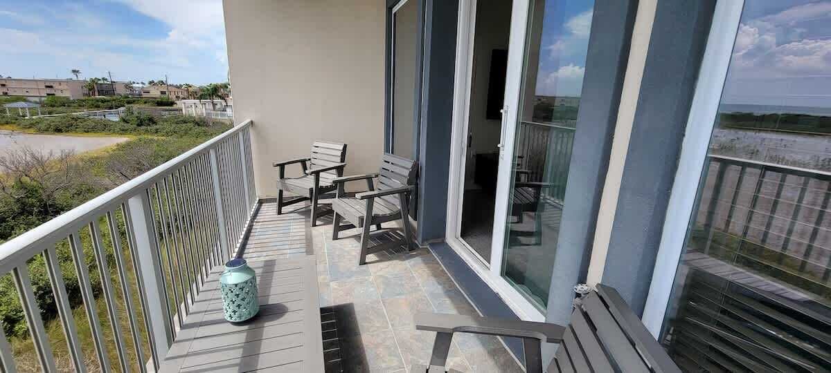 Un balcon avec un espace salon, une poubelle et une vue sur la plage.