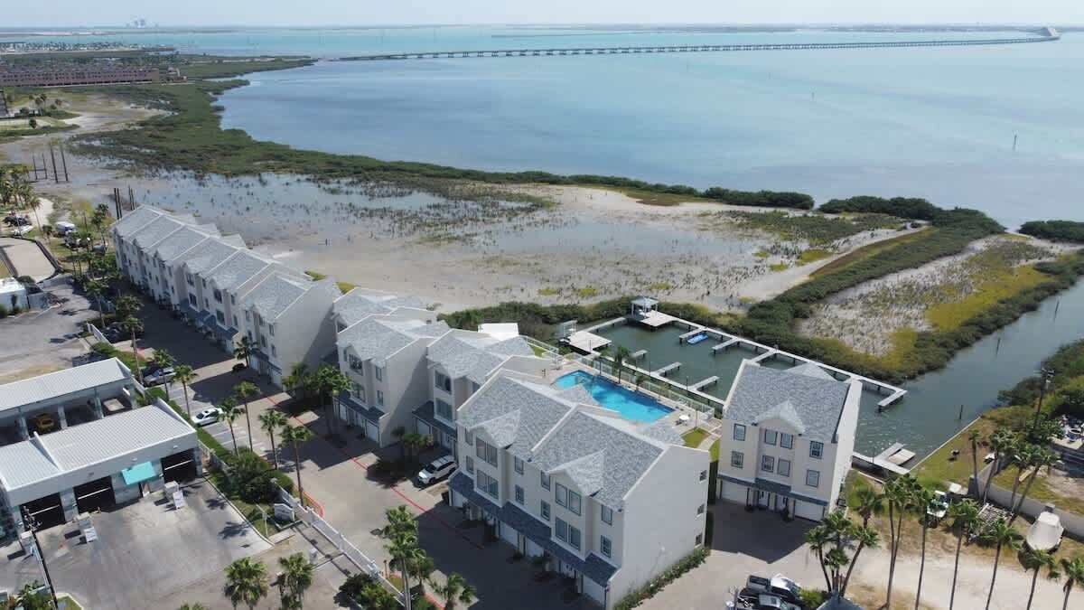 A hotel with a pool, beachfront view, and a pier in the background.
