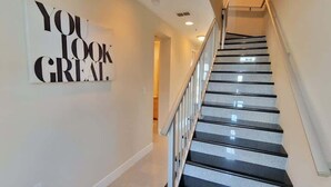 A staircase with a handrail and a wall-mounted sign that reads "YOU LOOK GREAT." - 3 Level Luxury Beachlike Pool - Killer Sunsets (South Padre Island)