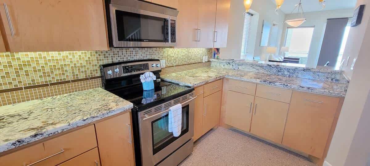 A kitchen with a microwave, stove, and granite countertop.