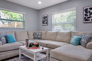 A living room with a sectional sofa, a coffee table, and a window with blinds.
