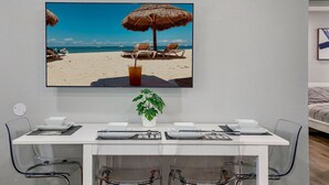 A dining area with a table set for two, a potted plant, and a framed picture of a beach scene. - 2BR Apt, 5 Min to Busch Gardens | Unit B, Sleeps 6, Remodeled, Tampa (Tampa)