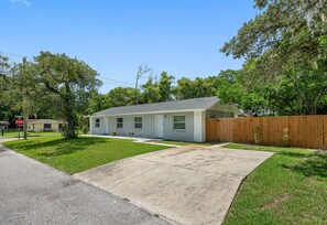 A single-story residential house with a front yard, a driveway, and a wooden fence. - 2BR Apt, 5 Min to Busch Gardens | Unit B, Sleeps 6, Remodeled, Tampa (Tampa)