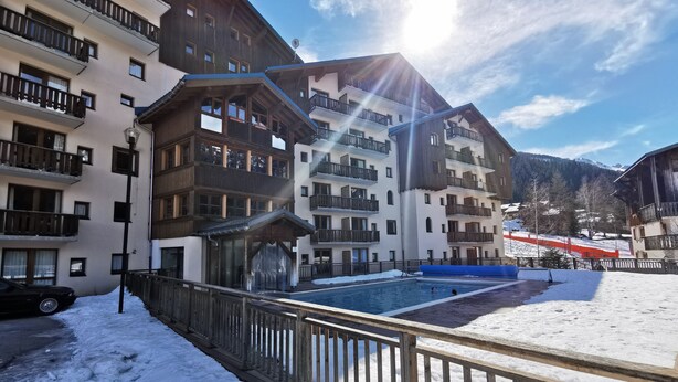 Un hôtel doté de nombreux balcons, d’une piscine et offrant, en toile de fond, un paysage enneigé.