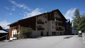 Un immeuble à plusieurs étages doté de balcons, d’un espace de stationnement et surplombant un ciel dégagé.