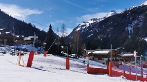 Une station de ski avec une piste enneigée, des remontées mécaniques et une vue sur les montagnes.