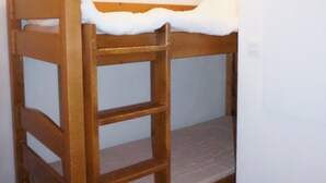 Un lit superposé avec une structure en bois et du linge de lit blanc.