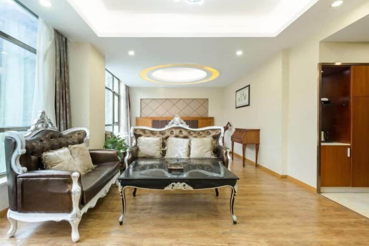 A spacious living room with a large sofa, a glass coffee table, and a wooden cabinet.