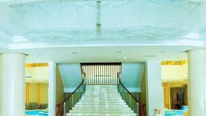 Una imponente escalera con barandilla de vidrio que conduce a una zona de recepción.