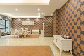 A hotel room with a dining area, a white dresser, and patterned wallpaper.