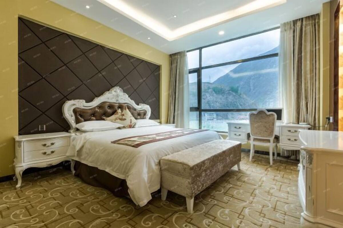 A bedroom with a large bed, a nightstand, a chair, and a dresser.