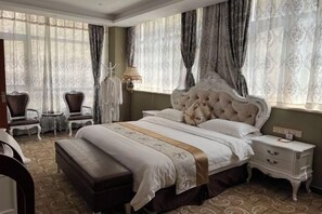 A hotel room with a large bed, a bedside table, a chair, and a lamp.