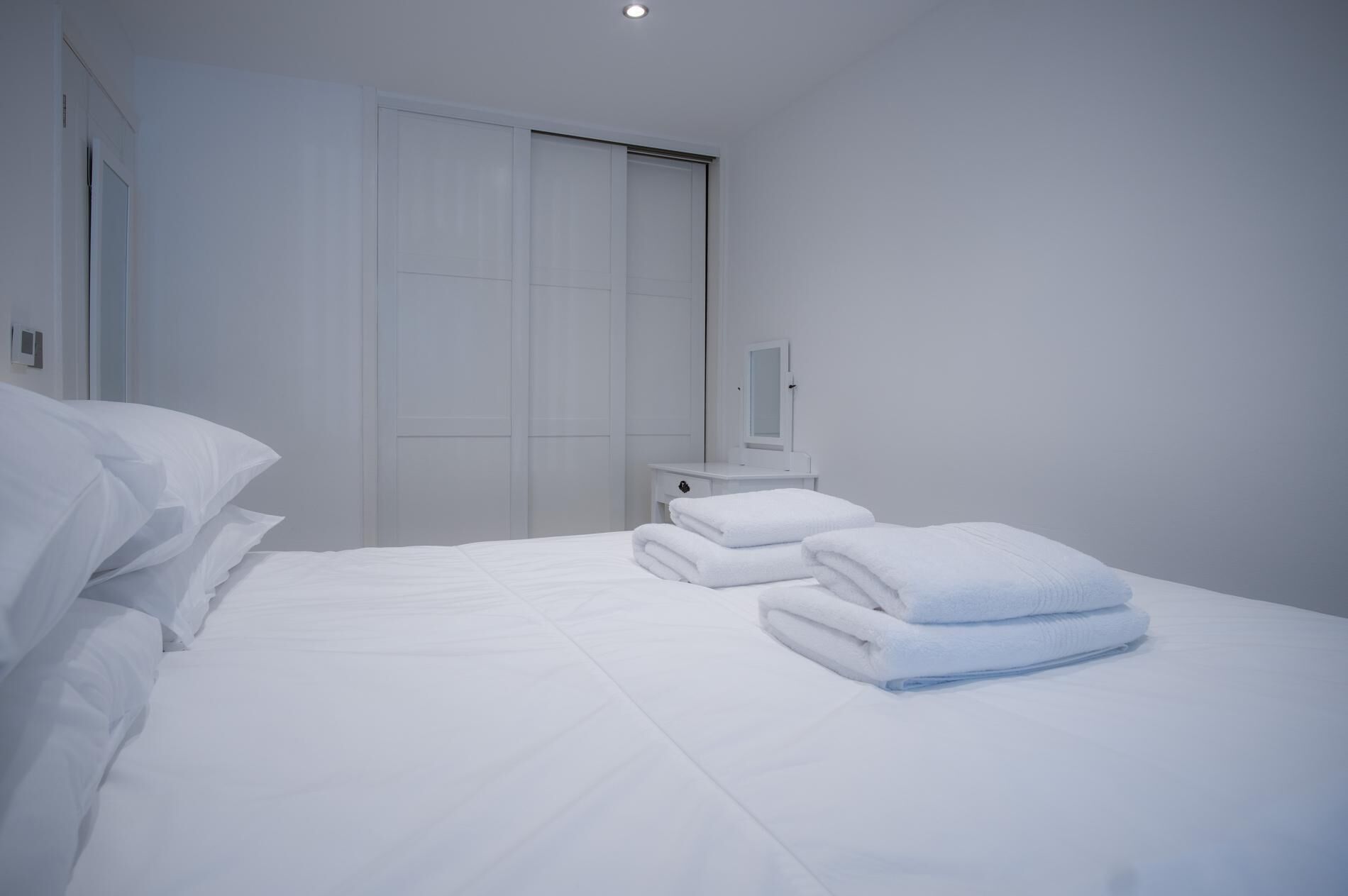Une chambre d’hôtel comprenant un lit, une table de chevet, un miroir et une armoire.