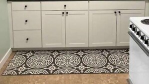 Una cocina con armarios blancos, encimera negra y salpicadero con diseño.