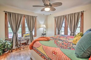 Een slaapkamer met een groot bed, een bureau en een plafondventilator.