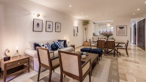 A modern living room with a sofa, chairs, a coffee table, and a dining area with a table and chairs. - Luxury Apartments with Rooftop & Jacuzzi (San Miguel de Allende)