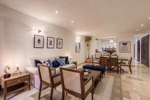 Una sala moderna con un sofá, sillones, una mesa de centro y un comedor con mesa y sillas.