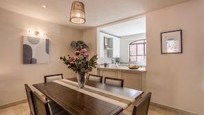 A dining area with a wooden table, chairs, a vase with flowers, and a hanging light fixture. - Luxury Apartments with Rooftop & Jacuzzi (San Miguel de Allende)
