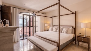 A four-poster bed with a bench, bedside tables, and a view of the outside. - Luxury Apartments with Rooftop & Jacuzzi (San Miguel de Allende)