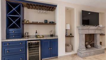 A kitchen with blue cabinets, a built-in wine cooler, and a stone fireplace.