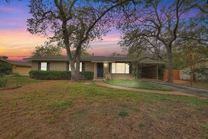 A single-story house with a front garage, a covered porch, and a well-maintained lawn. - Billie Goat Haus: Hot Tub, Fire Pit, Near Main St (Fredericksburg)