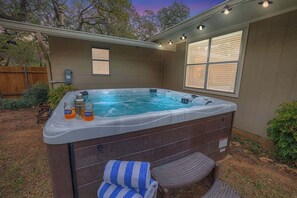 A hot tub with a wooden deck, a window with blinds, and a power outlet. - Billie Goat Haus-HotTub-Near Main St! (Fredericksburg)