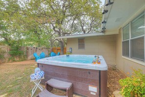 Un patio trasero con un jacuzzi, una terraza de madera y una cerca de madera.
