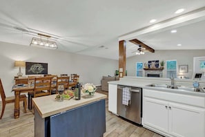A modern kitchen with white cabinetry, a wooden dining table, and a built-in island with a sink.