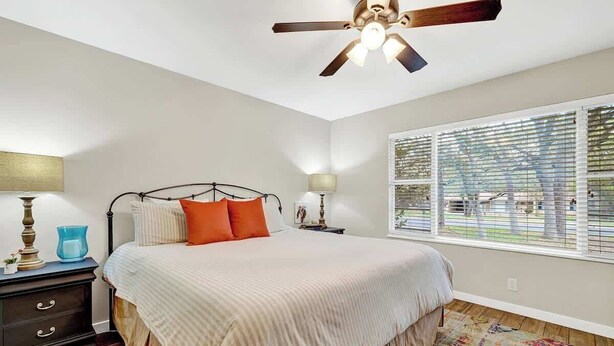 A bedroom with a bed, nightstand, lamp, and window with blinds.
